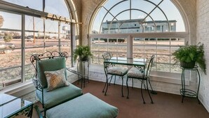 A sunroom with a glass ceiling, a green sofa, a table, and chairs.