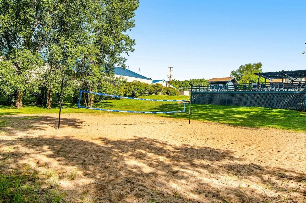 Een volleybalveld met een net, omringd door een hek en bomen.