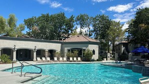 A swimming pool with lounge chairs and a building with arched doorways. - Well Located Condo in Scottsdale near TPC Golf 2BR 2BA (Scottsdale)