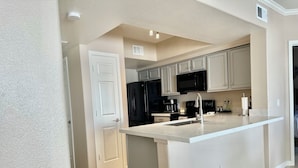 A modern kitchen with white cabinetry, a black refrigerator, and a stainless steel sink. - Well Located Condo in Scottsdale near TPC Golf 2BR 2BA (Scottsdale)