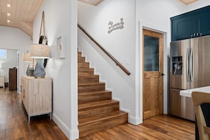 Eine moderne Küche mit einem Edelstahlkühlschrank, Holzschränken und einer Treppe zu einer weiteren Ebene.