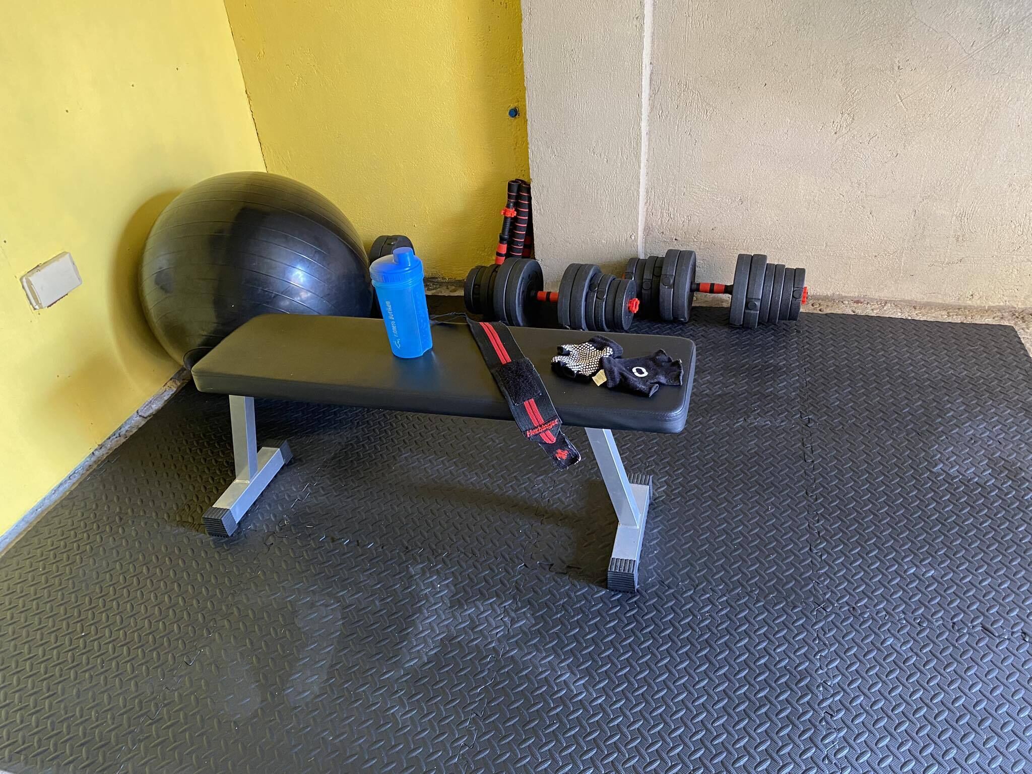 A gym with a bench, dumbbells, a kettlebell, and a medicine ball.