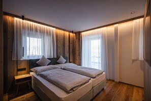 A bedroom with two beds, wooden paneling, and large windows with sheer curtains. - Chalet 'Rueper Hof Pracken' with Whirlpool, Private Terrace and Wi-Fi (Valdaora BZ)