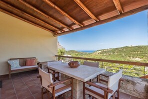 Un balcón con una mesa, sillas y vistas del paisaje.