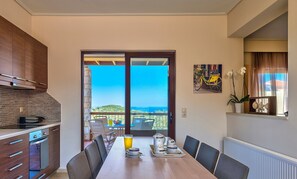 Ein Essbereich mit Meerblick, eine Küche mit Holzausstattung und ein Balkon mit einem gelben Fahrrad.