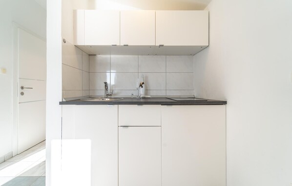 A compact kitchen with white cabinets, a black countertop, and a stainless steel sink. - Beautiful apartment in Krusevo (Krusevo)