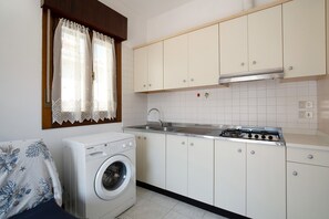 A compact kitchen with a washing machine, a sink, and cabinets.