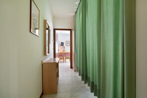 A hallway with a wooden desk, a chair, and a bed with a colorful headboard.