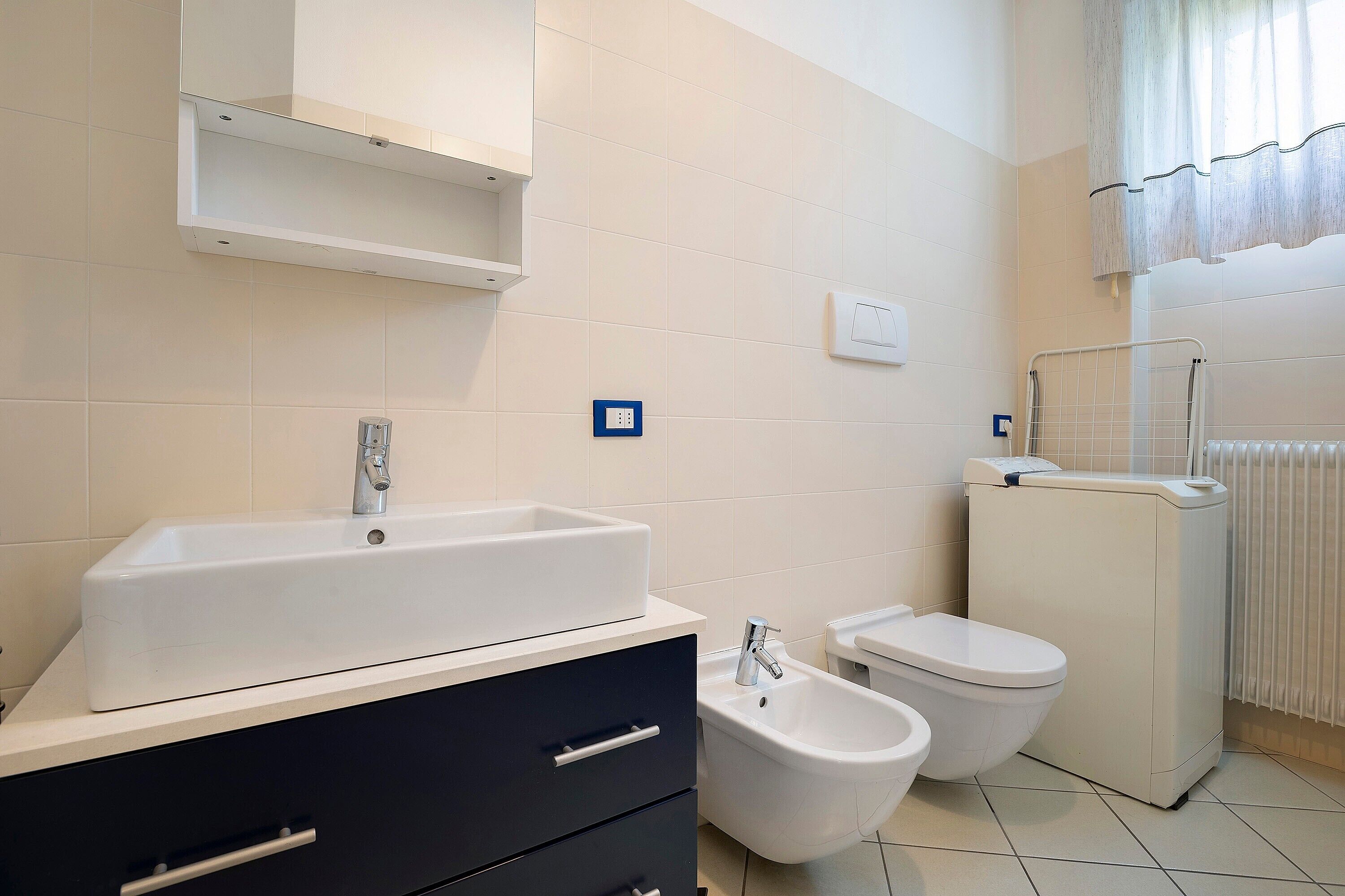 A bathroom with a sink, bidet, toilet, and a towel rack.