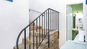 A staircase with stone steps and black metal railings, leading to a room with a green wall and a white sink.