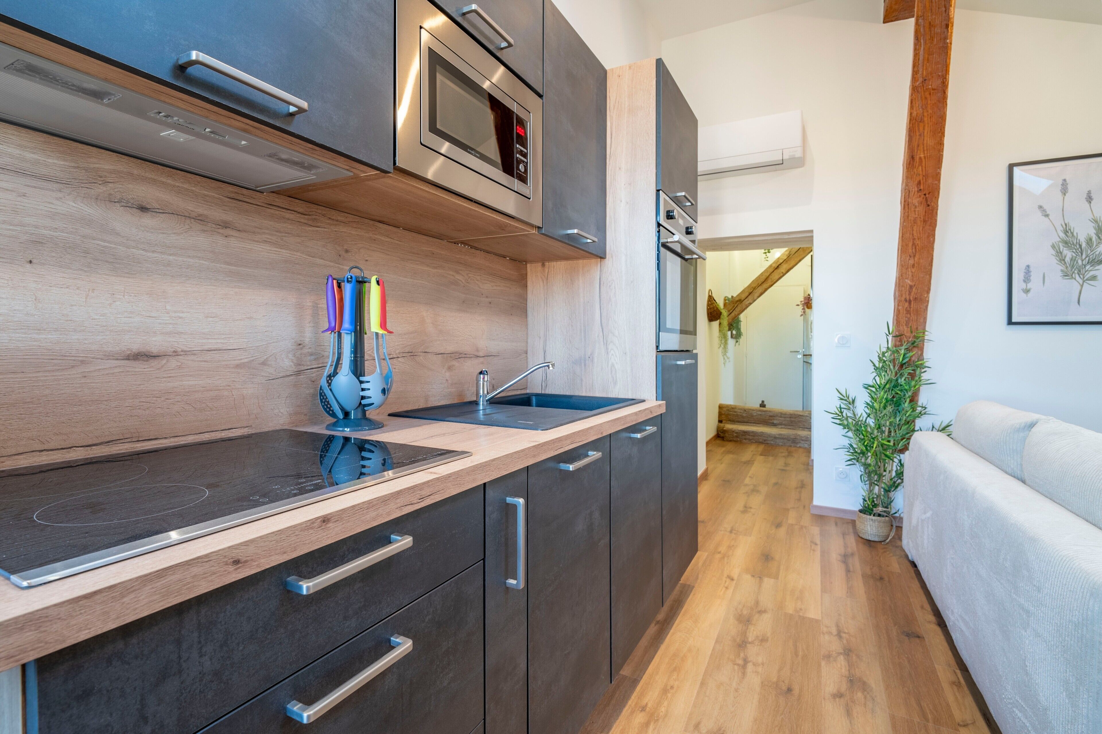 A modern kitchen with dark cabinetry, a wooden countertop, a built-in microwave, and a sink.