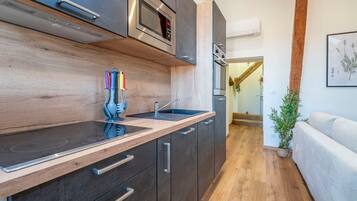 A modern kitchen with dark cabinetry, a wooden countertop, a built-in microwave, and a sink.