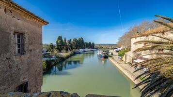 Un canal avec des bateaux, un bâtiment en pierre et un palmier.