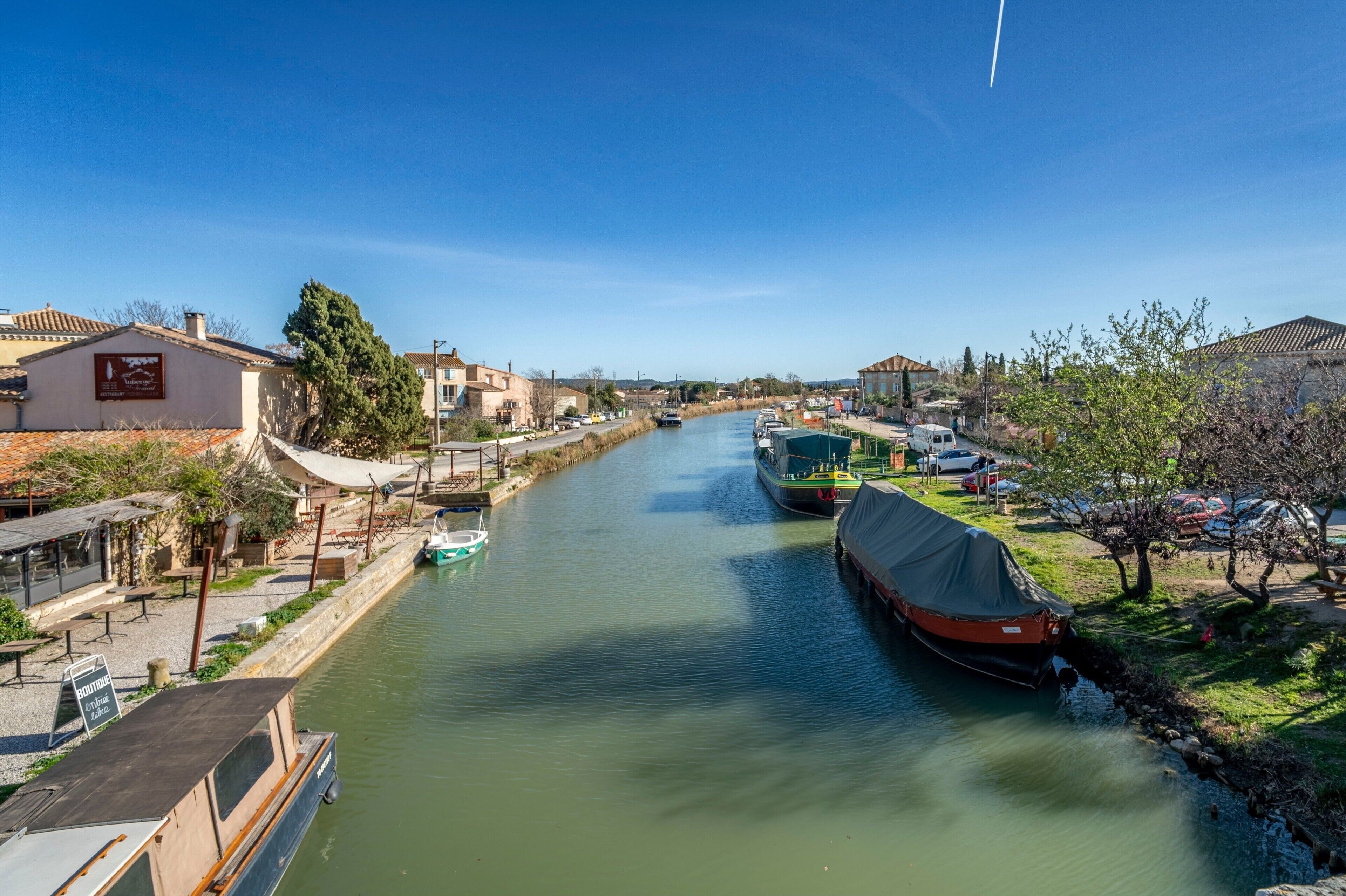 A canal with boats, a covered boat, and buildings along the banks.