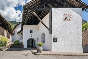 A building with a white exterior, a wooden staircase, and a stone wall.