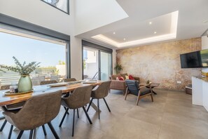 Ein modernes Interieur mit Essbereich, Sitzgelegenheiten, einem Flachbildfernseher und einem großen Fenster.