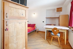 Une pièce comprenant un lit, une armoire en bois, une table avec une chaise et un radiateur.