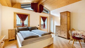 Ein Schlafzimmer mit einem Bett, einem Holzschrank und einem Esstisch mit Stühlen.