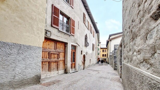 Eine enge Kopfsteinpflasterstraße, gesäumt von historischen Gebäuden mit Holzläden und Balkonen.