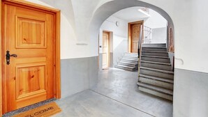 Ein Flur mit einer Holztür, einer Fußmatte und einer Treppe, die in einen anderen Raum führt.