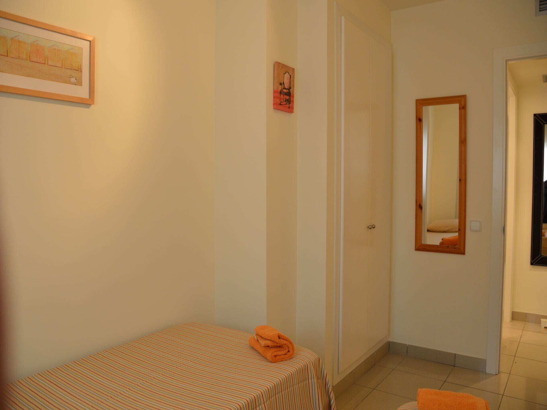 Una camera da letto con un letto, una porta, uno specchio e un quadro appeso al muro.