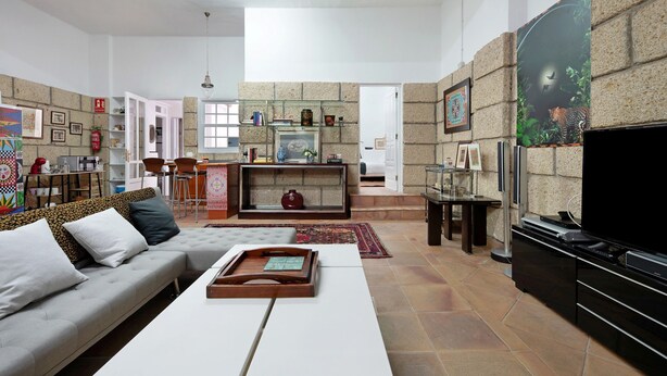 A living room with a sofa, coffee table, TV, fireplace, and stone wall decor. - Vacation Apartment 'Loft  Parque Santa Cruz' with Shared Terrace and Wi-Fi (Santa Cruz de Tenerife)