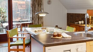 A modern kitchen with a built-in dishwasher, a dining area with a table and chairs, and a large window offering a view of the outdoors.