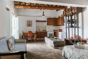 A rustic kitchen with stone flooring, wooden furniture, and a hanging light fixture. - Olive Guesthouse Junior Apartment with Sea View and Wi-Fi (Andros island)