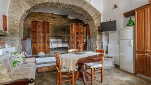 Un arco de piedra que da acceso a un comedor con mesa, sillas y un sofá.