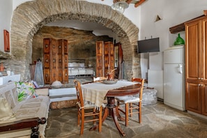 Un arco de piedra que da acceso a un comedor con mesa, sillas y un sofá.