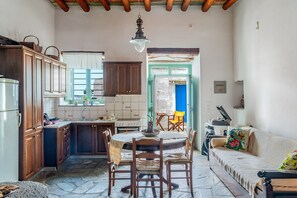 Cocina pequeña con armarios de madera, una mesa de comedor y un sofá.