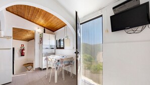 Una habitación con cocina, comedor y televisor montado en la pared.