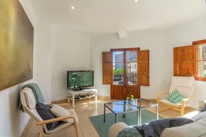 A living room with a television, a glass coffee table, a sofa, and a chair.