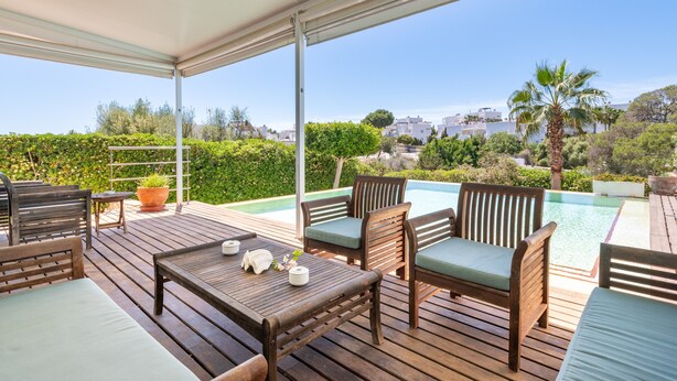 Un espace extérieur abrité, aménagé avec du mobilier en bois, une piscine et offrant une vue sur le paysage environnant.