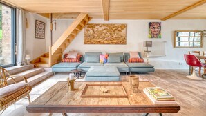 Un vaste espace de vie doté d’un plafond en bois, d’un grand canapé, d’une table basse et d’un escalier.