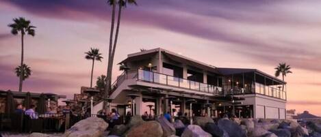 A beachfront property with a modern design, featuring a large balcony and a covered outdoor area.
