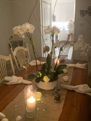 A beautifully set dining table with a centerpiece of white orchids and a lit candle.