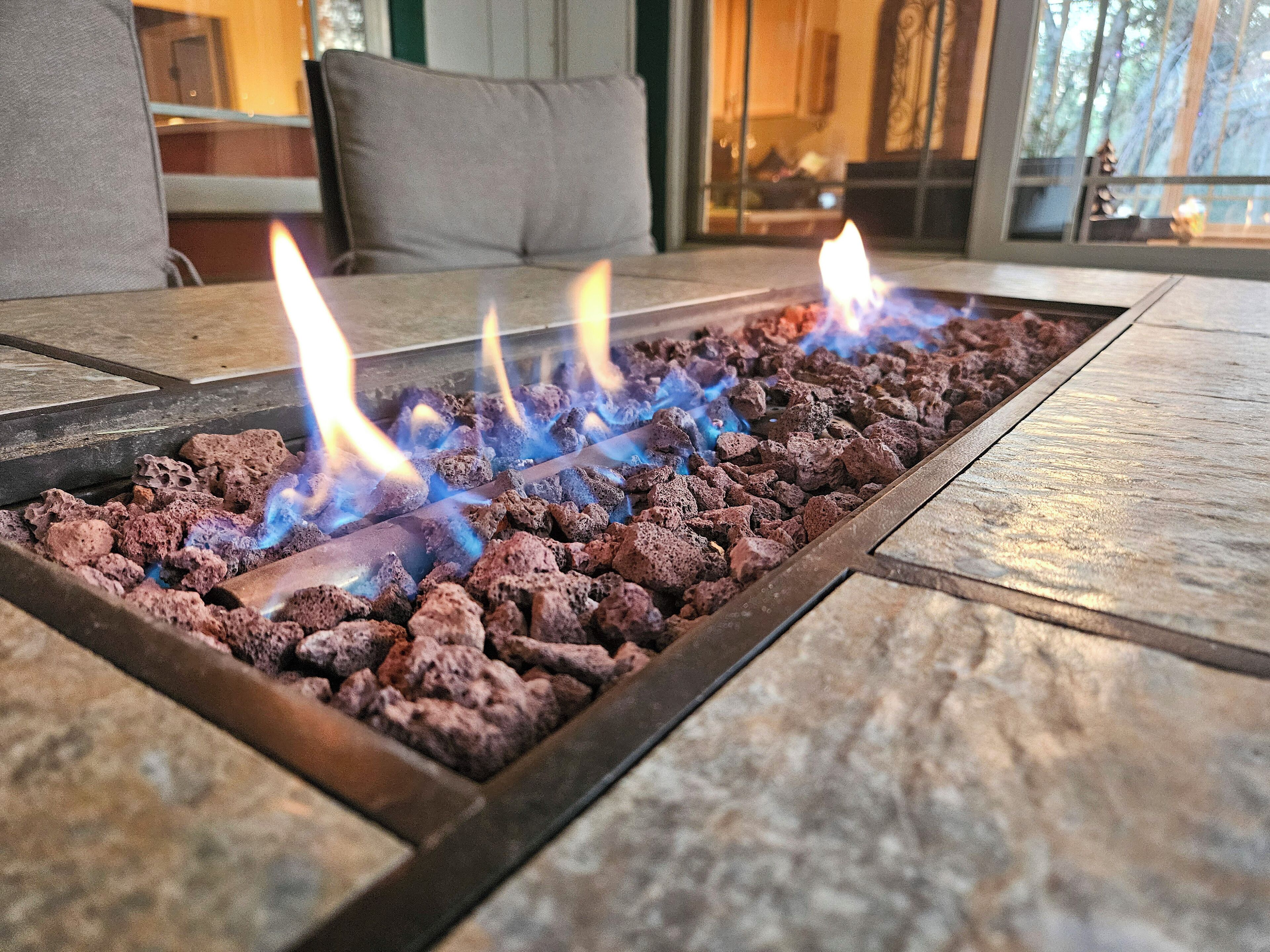 A fire feature with multiple flames burning through a bed of lava rocks.