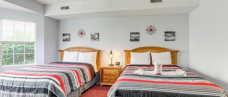 A hotel room with two beds, a ceiling fan, and artwork on the walls.