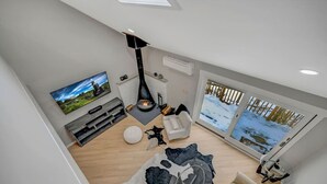 A modern living room with a fireplace, a television, and a large window with a snowy view.