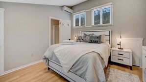 A bedroom with a bed, bedside tables, a nightstand, and a window with blinds.