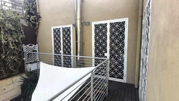 A balcony with metal railings, a white canopy, and a wall with decorative metal grilles. - LunaBedRoma - Short rentals in the green (Roma)