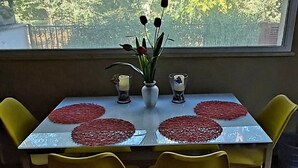 A dining table with a vase of flowers, two candles, and red placemats. Four yellow chairs surround the table. - LunaBedRoma - Short rentals in the green (Roma)