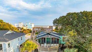 Une propriété située en bord de mer, dotée d’une terrasse en bois et d’un balcon offrant une vue sur l’océan.