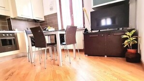 A modern kitchen with a dining area, wooden flooring, and a large flat-screen TV. - Luxury Verona Apartment City Centre (Verona)