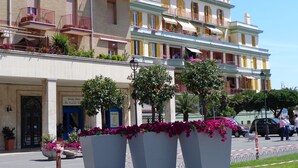 A multi-story hotel with balconies, potted plants, and a blue entrance door. - Ostia-apartment 50 mt from the beach, near historic center-sea view (Lido di Ostia)
