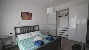 A modern bedroom with a bed, a bedside table, a nightstand, a wardrobe, and a hanging light fixture. - Ostia-apartment 50 mt from the beach, near historic center-sea view (Lido di Ostia)