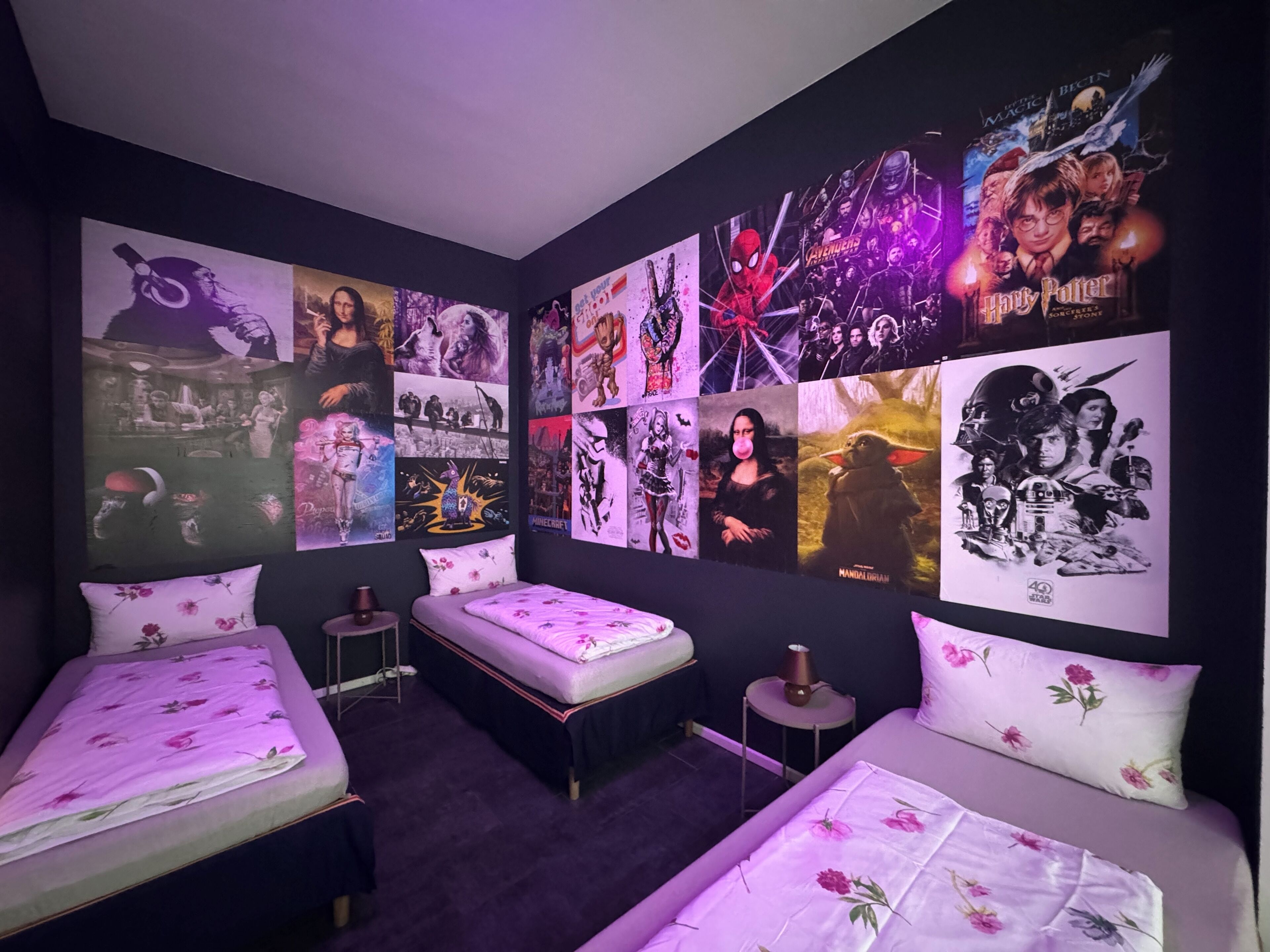 Una habitación con dos camas, una mesita pequeña y una pared decorada con carteles de películas.