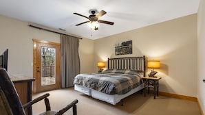 A bedroom with a bed, two bedside lamps, a ceiling fan, a wooden chair, a wooden desk, and a door leading to a balcony. - Private Hot Tub Getaway with Peaceful Views, Free Silver Dollar Tickets & Near Branson Shows (Branson)