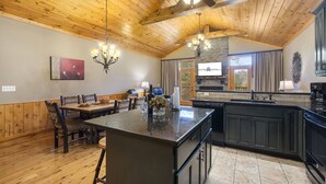 A spacious kitchen with a large island, wooden ceiling, and a stone accent wall. - Private Hot Tub Getaway with Peaceful Views, Free Silver Dollar Tickets & Near Branson Shows (Branson)